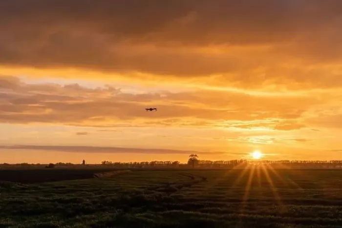 Framed Print : A drone flying over green springtime meadows with a colorful orange sunset sky behind Framed Print : A drone flying over green springtime meadows with a colorful orange sunset sky behind