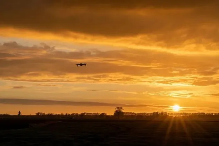 Framed Print : A drone flying over green springtime meadows with a colorful orange sunset sky behind Framed Print : A drone flying over green springtime meadows with a colorful orange sunset sky behind