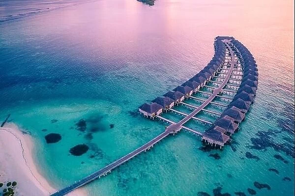 Drone photo wooden water villas seen from above and an amazing blue lagoon crystal clear water close to tropical lagoon. Amazing summer