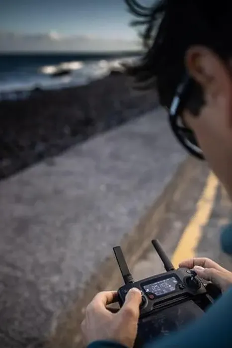 Framed Print : Drone pilot in action, taking aerial photos and capturing footage of waves crashing on a beach