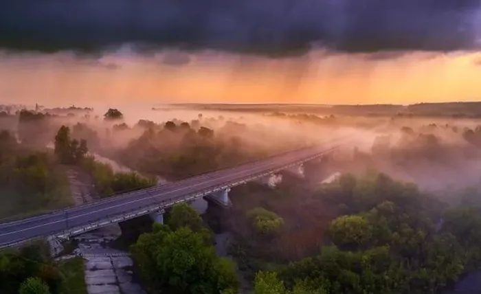 Framed Print : Drone view of the bright dawn over the highway overpass, forest and misty meadow