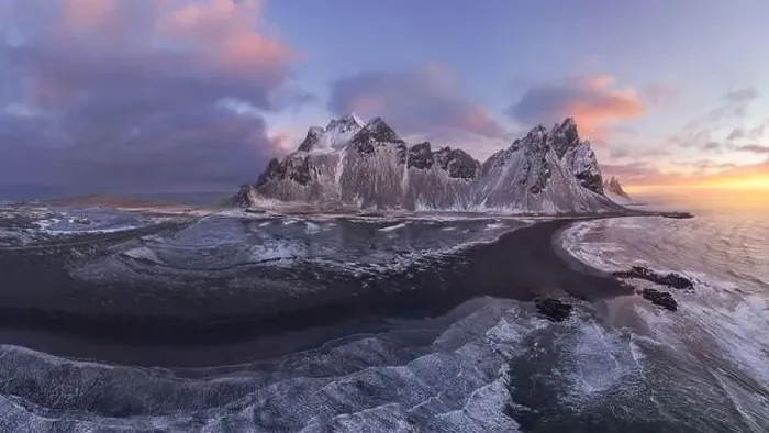 Framed Print : Drone view of calm frozen endless sea surrounding high rocky snowy Vestrahorn mountain during picturesque sunset in Framed Print : Drone view of calm frozen endless sea surrounding high rocky snowy Vestrahorn mountain during picturesque sunset in