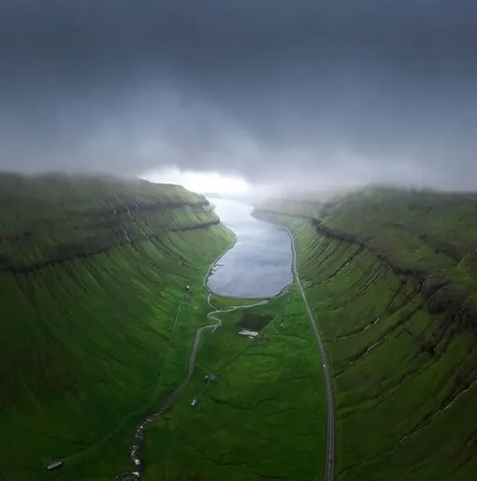 Framed Print : Drone view of curvy roads going on green mossy fjord near calm sea water against gray overcast sky on stormy day Framed Print : Drone view of curvy roads going on green mossy fjord near calm sea water against gray overcast sky on stormy day