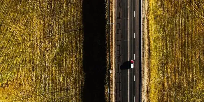 Framed Print : Drone view of moving red car on country side road with beautiful green field around