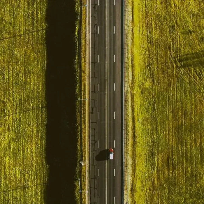 Framed Print : Drone view of moving red car on country side road with beautiful green field around