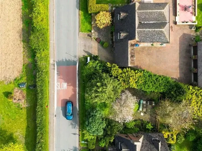 Framed Print : Drone top down view of a Slow road markings seen on a dangerous rural English road. A single car passes at speed Framed Print : Drone top down view of a Slow road markings seen on a dangerous rural English road. A single car passes at speed
