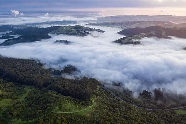 Early morning light illuminates fog as it rolls through valleys in Northern California. Just west of these hills and valleys is San Francisco Bay