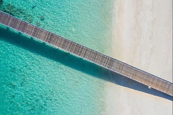 Exotic aerial view of turquoise water with wooden jetty on Maldives island, beautiful shallow sea water and corals with white sand. Motivational