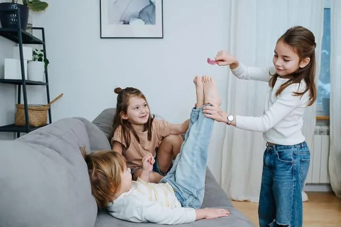 Framed Print : Experimenting girls tickling boy's feet with feather. He straightening his legs towards it, curious about the sensation Framed Print : Experimenting girls tickling boy's feet with feather. He straightening his legs towards it, curious about the sensation