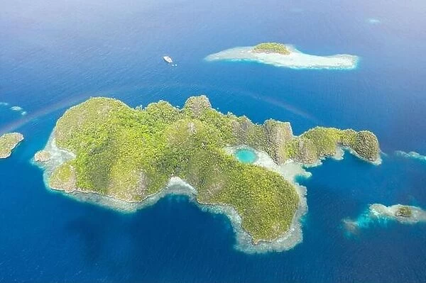 A faint rainbow curves over a scenic set of limestone islands in Raja Ampat, Indonesia. This remote region is known for its high marine biodiversity