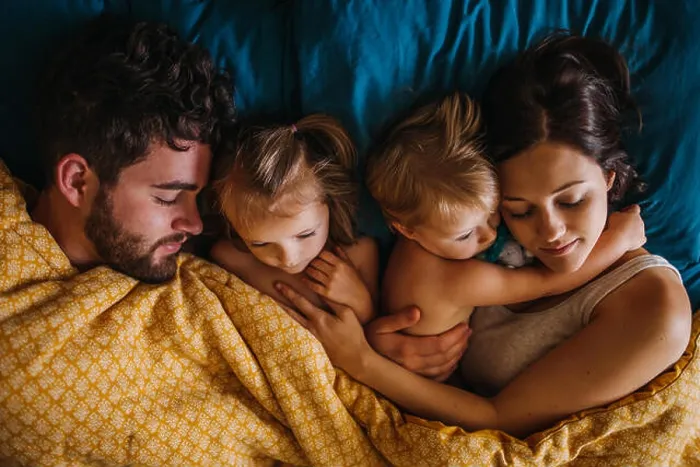 Framed Print : Family of four cuddling in bed with children