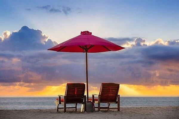 Fantastic romantic sunset, two sun beds, loungers, umbrella. White sand, sea view with horizon, colorful twilight sky, calm, relax seaside. Inspire