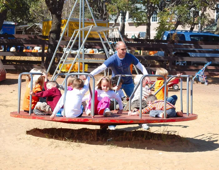Framed Print : Father pushing kids on a merry-go-round at a playground Framed Print : Father pushing kids on a merry-go-round at a playground