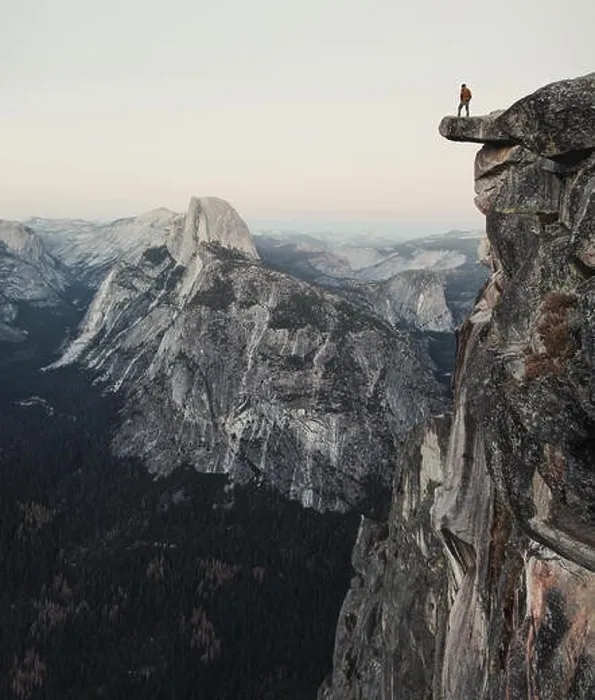 Framed Print : A fearless hiker is standing on an overhanging rock enjoying the view towards famous Half Dome at Glacier Point in