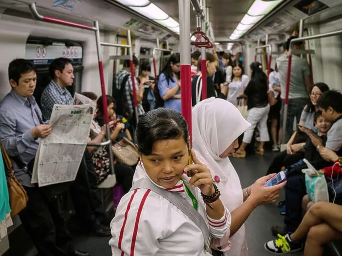 Framed Print : FILE--Two domestic workers use their mobile phones in a subway train in Hong Kong Framed Print : FILE--Two domestic workers use their mobile phones in a subway train in Hong Kong