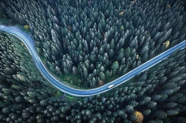 Flight over the autumn mountains with road serpentine and pine forest. Top down view. Landscape photography
