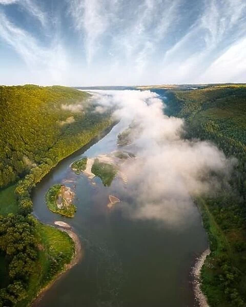 Flight through majestic foggy river and lush green forest at sunrise time. Landscape photography. Dnister, Ukraine, Europe