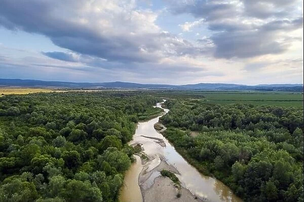 Flight through majestic river Dnister and lush green forest at sunset time. Ukraine. Landscape photography