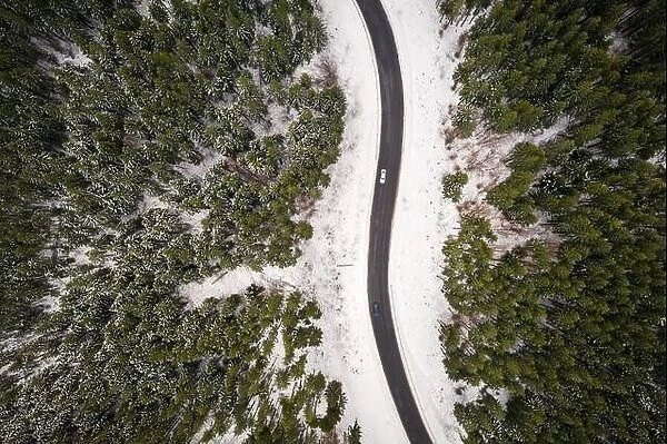 Flight over the winter mountains with road serpentine and snowy forest. Top down view. Landscape photography