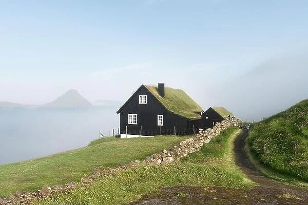 Foggy morning view of a house with typical turf-top grass roof in the Velbastadur village on Streymoy island, Faroe islands, Denmark
