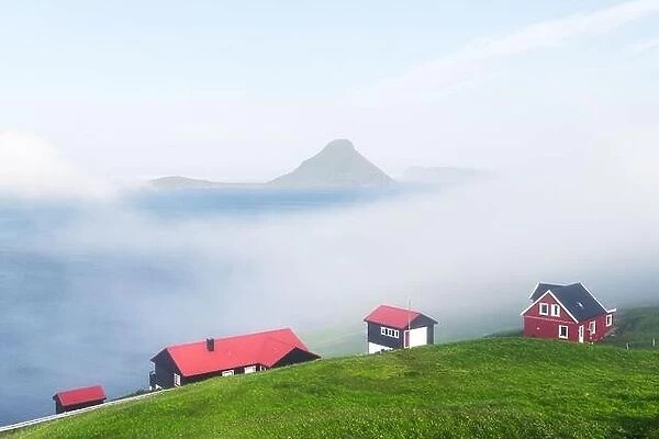Foggy morning view of a houses with red roof in the Velbastadur village on Streymoy island, Faroe islands, Denmark. Landscape photography