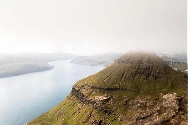 Foggy mountain peaks and clouds covering sea and mountains. Panoramical view from famous place - Sornfelli on Streymoy island, Faroe islands