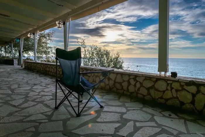 Framed Print : A folding chair on the covered patio of a seaside building with a great view of the sea and sunset sky clouds Framed Print : A folding chair on the covered patio of a seaside building with a great view of the sea and sunset sky clouds