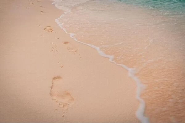 Footprints in the sand near the sea. Beach, wave and footprints at sunset time, dream beach landscape, waves