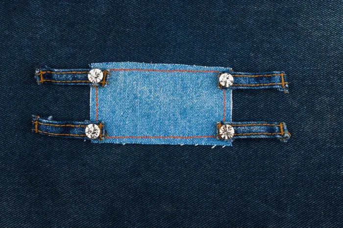 Framed Print : Frame with four straps jeans and rhinestones, lies on the dark denim, with space for your text Framed Print : Frame with four straps jeans and rhinestones, lies on the dark denim, with space for your text