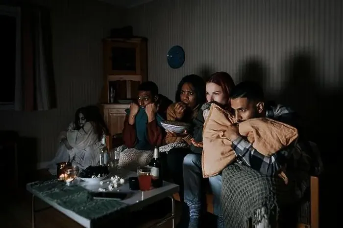 Framed Print : Frightened multiracial friends watching scary movie while ghost sitting in corner at cabin