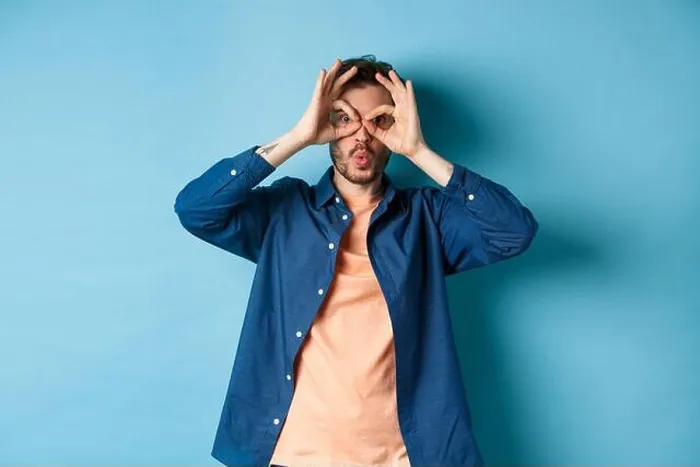 Framed Print : Funny young man looking through hand binoculars and say wow Framed Print : Funny young man looking through hand binoculars and say wow