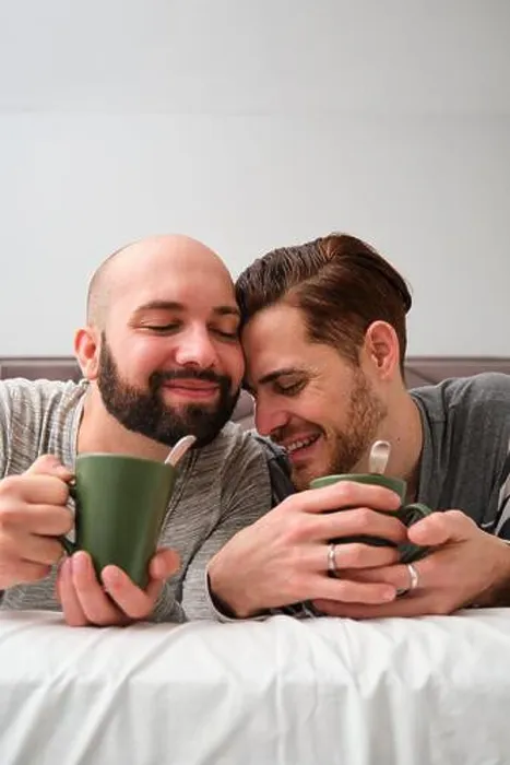 Framed Print : Gay couple in love drinking coffee in bed together Framed Print : Gay couple in love drinking coffee in bed together