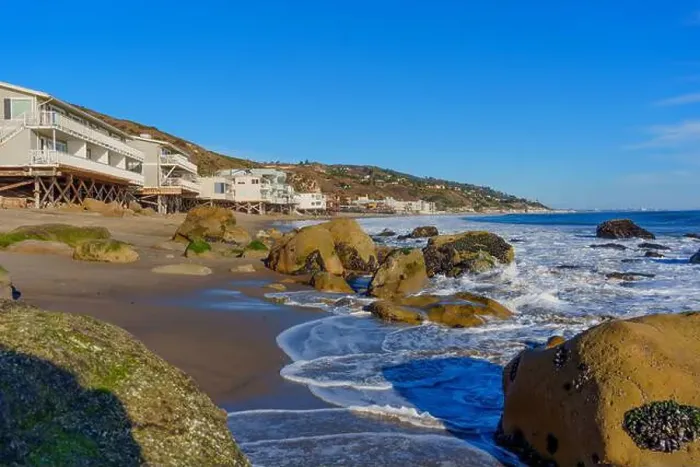 Framed Print : Gentle waves crashing on rocky shore at Malibu Beach with coastal homes in the backdrop Framed Print : Gentle waves crashing on rocky shore at Malibu Beach with coastal homes in the backdrop