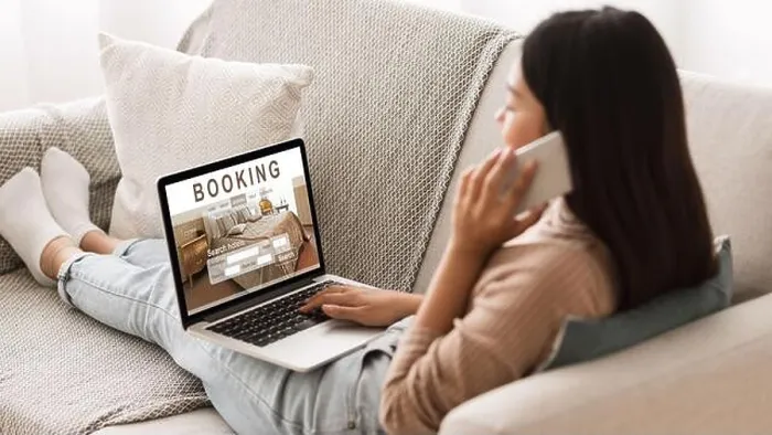 Framed Print : Girl booking hotel online, talking on phone with reservation team