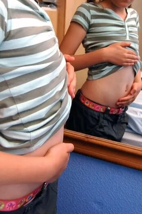 Framed Print : Girl looking at her tummy in a mirror Framed Print : Girl looking at her tummy in a mirror