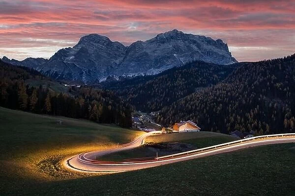 Glowing road at the autumn Dolomite Alps. Amazing landscape with lighting road and snowy mountains on background at San Genesio village location