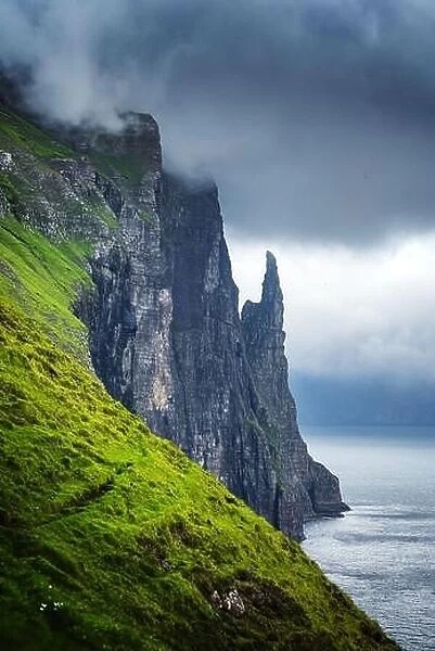 Gorgeous faroese landscape with famous Witches Finger cliffs and dramatic cloudy sky from Trollkonufingur viewpoint
