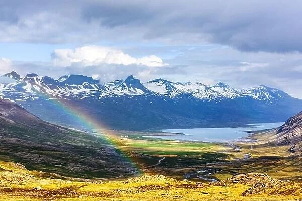 Gorgeous Icelandic landscape with fjord and rainbow on snowy mountains background