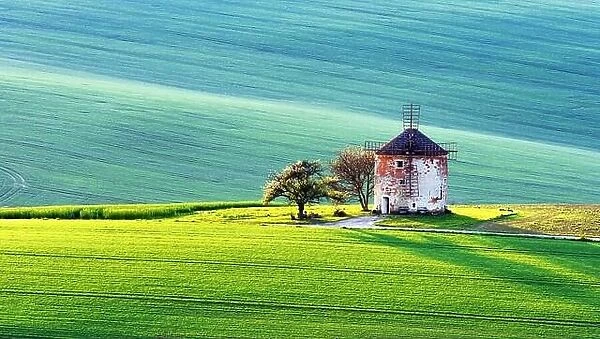 Gorgeous rural landscape with old windmill and green sunny spring hills. South Moravia region, Czech Republic