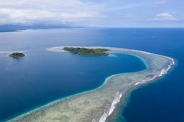 A gorgeous, tropical island is surrounded by reef in Papua New Guinea. This remote area is part of the Coral Triangle due to its marine biodiversity