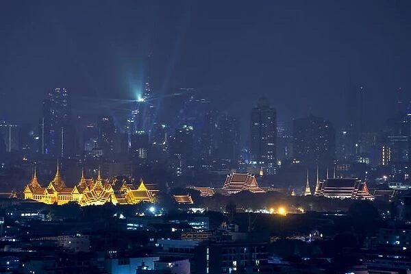 Grand palace with Bangkok city skyscrapers at night in Bangkok, Thailand