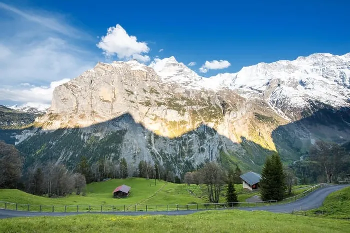 Framed Print : Green fields and famous stunning touristic town with high cliffs in background, Lauterbrunnen, Bernese, Oberland, Switzerland Framed Print : Green fields and famous stunning touristic town with high cliffs in background, Lauterbrunnen, Bernese, Oberland, Switzerland