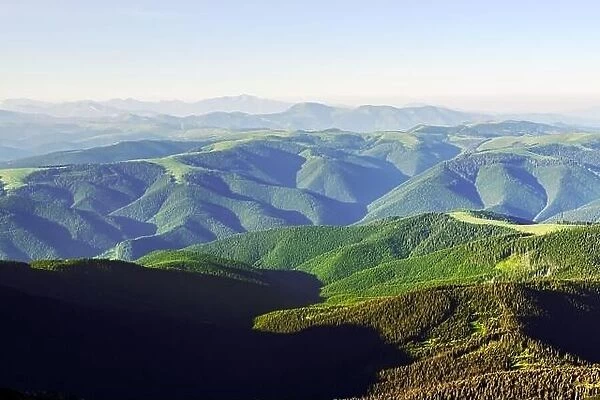 Green mountains range in summer time. Breathtaking view on hills covered by lush forest. Landscape photography