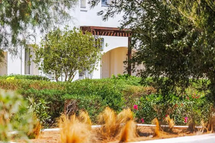 Framed Print : Green shrubs and trees in garden near white house with wooden pergola. Crete. Greece