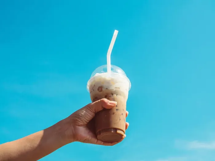Framed Print : Hand holding a cup of iced coffee on blue sky background Framed Print : Hand holding a cup of iced coffee on blue sky background