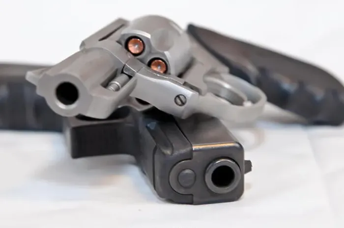 Framed Print : Two handguns, a silver 357 magnum revolver on top of a black 9mm pistol on a white background Framed Print : Two handguns, a silver 357 magnum revolver on top of a black 9mm pistol on a white background
