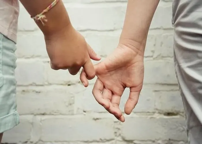 Framed Print : Two hands belonging to children, one boy and one girl, tentatively hold fingers against a white brick wall background Framed Print : Two hands belonging to children, one boy and one girl, tentatively hold fingers against a white brick wall background