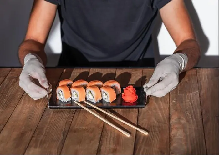 Framed Print : Hands in rubber gloves serve sushi on a wooden table. Sushi menu Framed Print : Hands in rubber gloves serve sushi on a wooden table. Sushi menu