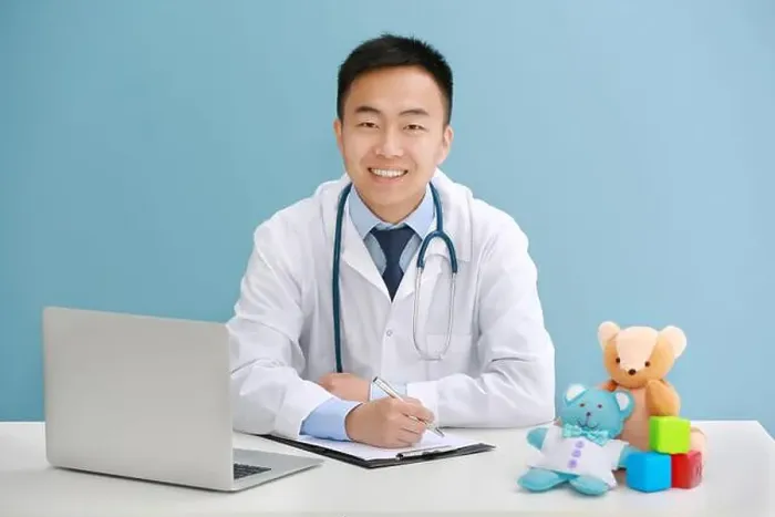 Framed Print : Handsome pediatrician doctor with laptop and teddy bear in office Framed Print : Handsome pediatrician doctor with laptop and teddy bear in office