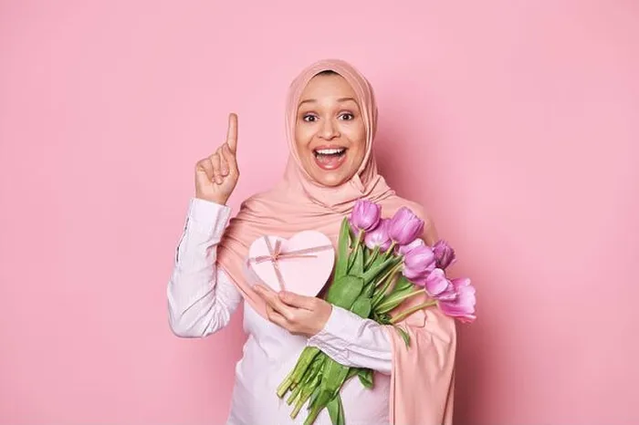 Framed Print : Happy amazed pregnant Muslim woman in pink hijab, holds a bouquet of tulips and gift box, points finger up at copy space Framed Print : Happy amazed pregnant Muslim woman in pink hijab, holds a bouquet of tulips and gift box, points finger up at copy space